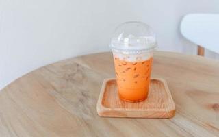 Iced Thai tea in plastic cup on wooden table photo