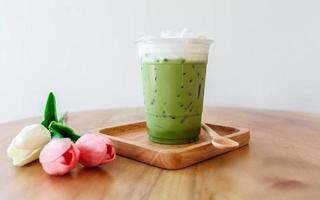 Plastic cup of iced green tea on wooden table photo