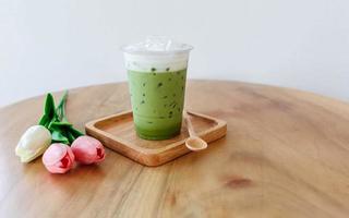 Plastic cup of iced green tea on wooden table photo