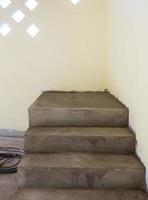 Unfinished cement staircase near the soft yellow wall. photo