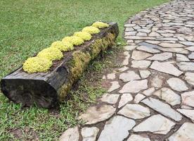 Log flower pot near the brick tile path. photo