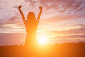 Silhouette of woman praying over beautiful sky background photo