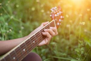 joven hipster tocando la guitarra para relajarse en sus vacaciones, disfrutar del aire natural y fresco. foto