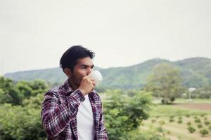 handsome hipster bearded man with cup of morning coffee walking in park. photo