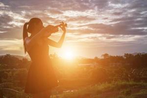 mujer joven tocando el violín con montañas en el fondo foto