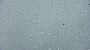 Regentropfen, die ein Fenster in einer Nahaufnahme herunterlaufen. video