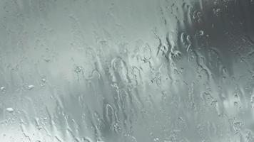 Time lapse rain drops in front of dark clouds on a glass window. video