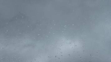 Time lapse rain drops in front of dark clouds on a glass window. video