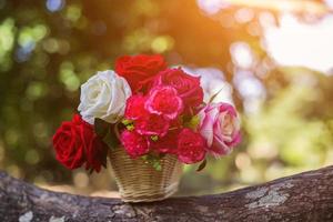 Mixed beautiful flowers in the vase on wooden background photo