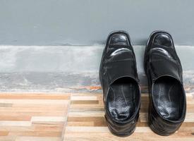 Old leather shoes is laying on the house wall. photo