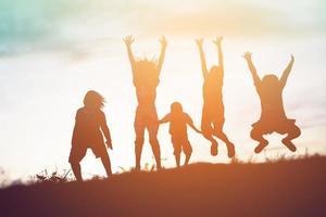 silueta de niños felices y puesta de sol feliz foto