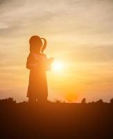 silueta de niño, momentos de alegría del niño. en la puesta de sol de la naturaleza foto