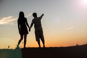 silhouette of a man and woman holding hands with each other, walking together. photo