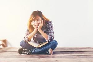 Young hipster woman holding books and pointing up on isolated white background. photo