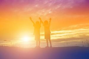 silueta de niños felices y puesta de sol feliz foto