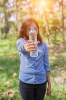 Beautiful young woman drinking water in the morning after finished jogging photo