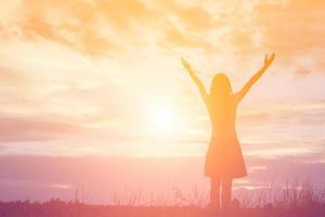 Silhouette of woman praying over beautiful sky background photo