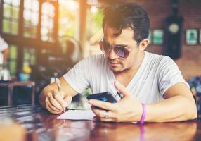 Young man with smartphone smiling relaxing at cafe. photo