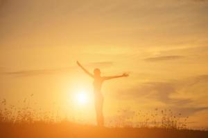 Silhouette of woman praying over beautiful sky background photo