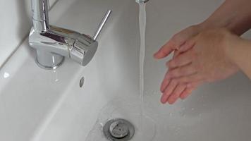 Washing hands with soap in a chrome metal sink with water from a water tap video