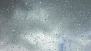 Time lapse rain drops in front of dark clouds on a glass window. video