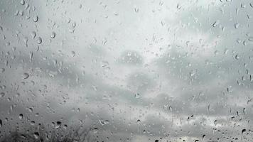 Time lapse rain drops in front of dark clouds on a glass window. video