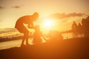 Silhouettes of mother and little daughter walking at sunset photo