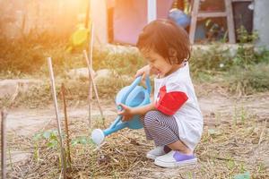 Little girl watering tree with watering pot photo