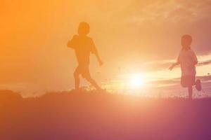 silueta de niños felices y puesta de sol feliz foto