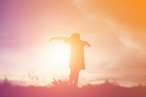 silueta de niño, momentos de alegría del niño. en la puesta de sol de la naturaleza foto