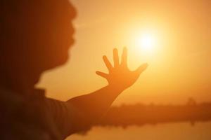 hands forming a heart shape with sunset silhouette photo