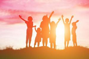 silueta de niños felices y puesta de sol feliz foto