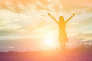 Silhouette of woman praying over beautiful sky background photo