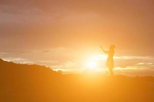 Silhouette of woman praying over beautiful sky background photo