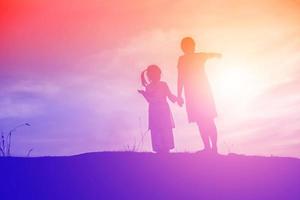 Mother encouraged her daughter out of the shadows at sunset. photo