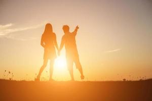 silhouette of a man and woman holding hands with each other, walking together. photo