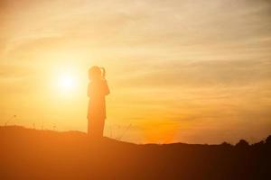 silueta de niño, momentos de alegría del niño. en la puesta de sol de la naturaleza foto