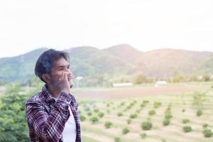 Hipster man smoking cigarette, standing behind a mountain. Among the fresh air in the morning. photo