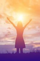 Silhouette of woman praying over beautiful sky background photo