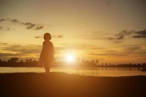 Silhouettes of mother and little daughter walking at sunset photo