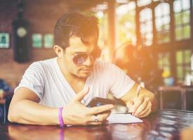 Young man with smartphone smiling relaxing at cafe. photo