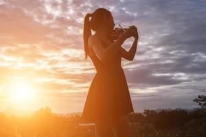 mujer joven tocando el violín con montañas en el fondo foto