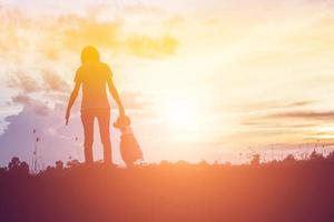 a silhouette of a happy young girl child the arms of his loving mother for a hug, in front of the sunset in the sky on a summer day. photo