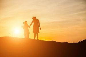 madre animó a su hija a salir de las sombras al atardecer. foto