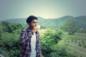 handsome hipster bearded man with cup of morning coffee walking in park. photo