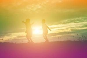 silueta de niños felices y puesta de sol feliz foto