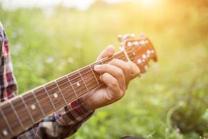 joven hipster tocando la guitarra para relajarse en sus vacaciones, disfrutar del aire natural y fresco. foto