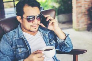 Young man with smartphone smiling relaxing at cafe. photo