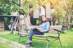 Hipster charming girl relaxing in the park while read book, Enjoy nature around. photo
