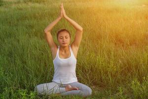 Yoga in the city beautiful young fit woman wearing sportswear meditating, breathing, sitting with crossed legs in Half Lotus Posture on the street on summer day, Ardha Padmasana, copy space photo